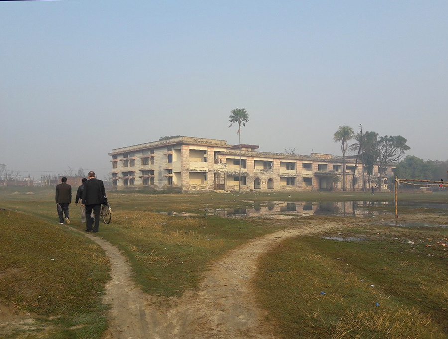 Tiimi polulla matkalla koulutuspaikalle Sirahassa, raunioitunut rakennus.