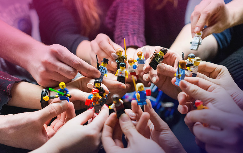 Useita ihmisten käsiä, joissa erilaisia Lego-hahmoja.