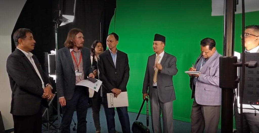 Nepalese project specialists with Boris Janca at a studio with green screen fabric behind them. 