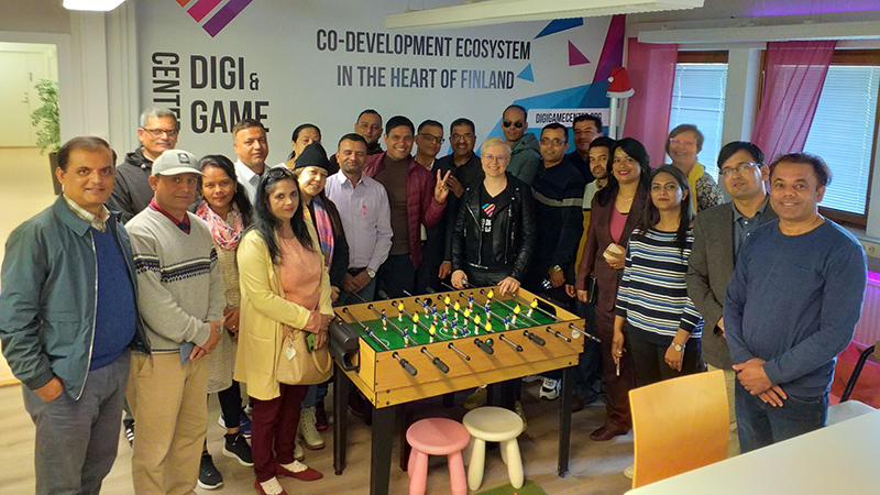 People in a group photo at Digi center Jamk, they are standing behind a table football.