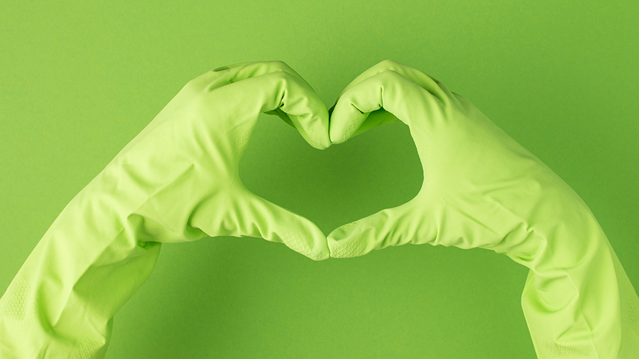 Vihreisiin kumihanskoihin puetut kädet muodostavat sydänkuvion.