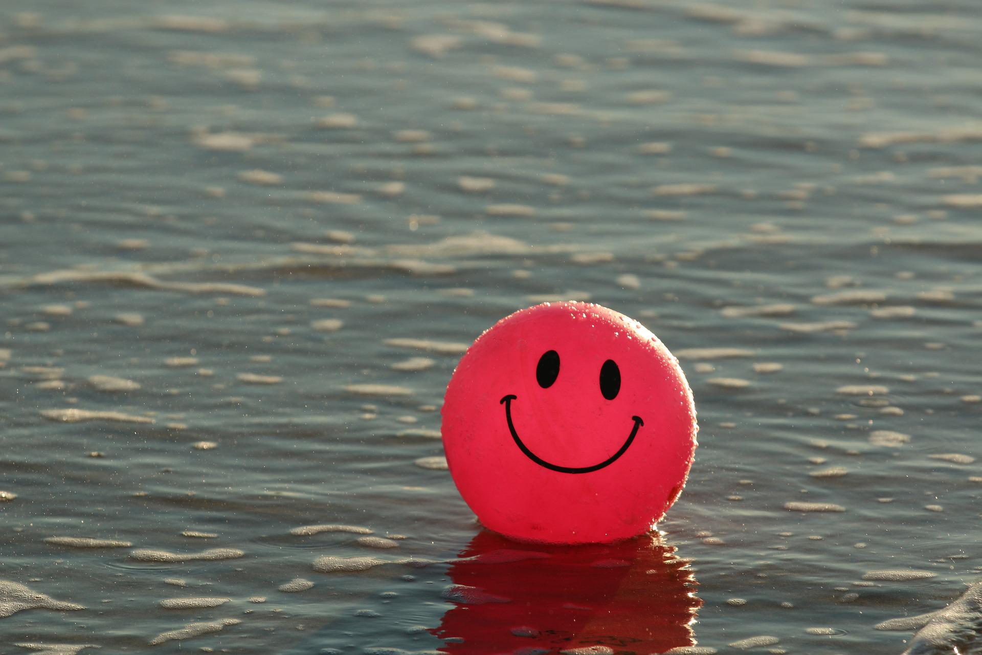 Punainen ilmapallo, jossa on hymynaama, kelluu veden pinnalla