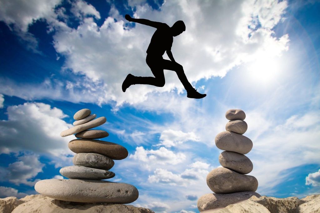 Ihminen hyppää kivikasasta toiseen kivikasaan